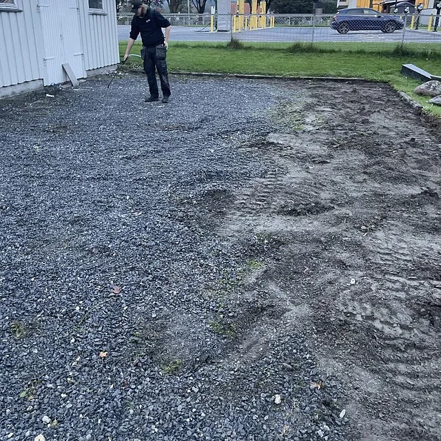 Jevnet grusområde eller gårdsplass klar for steinlegging ved et hvitt hus.