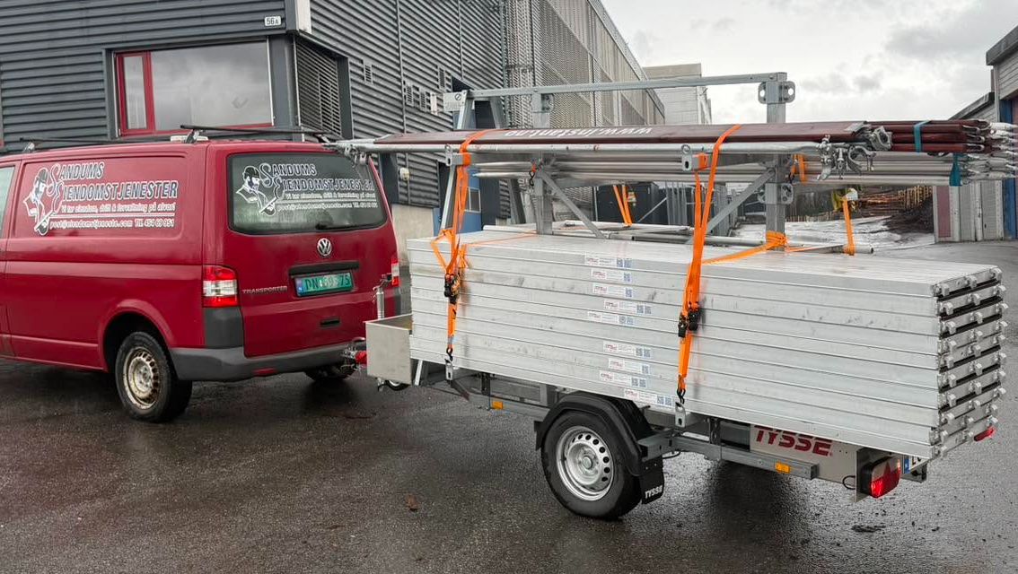 Rød bil med stillas på henger