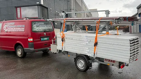 Rød bil med stillas på henger