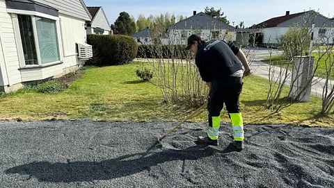 Mann planerer grus med rake